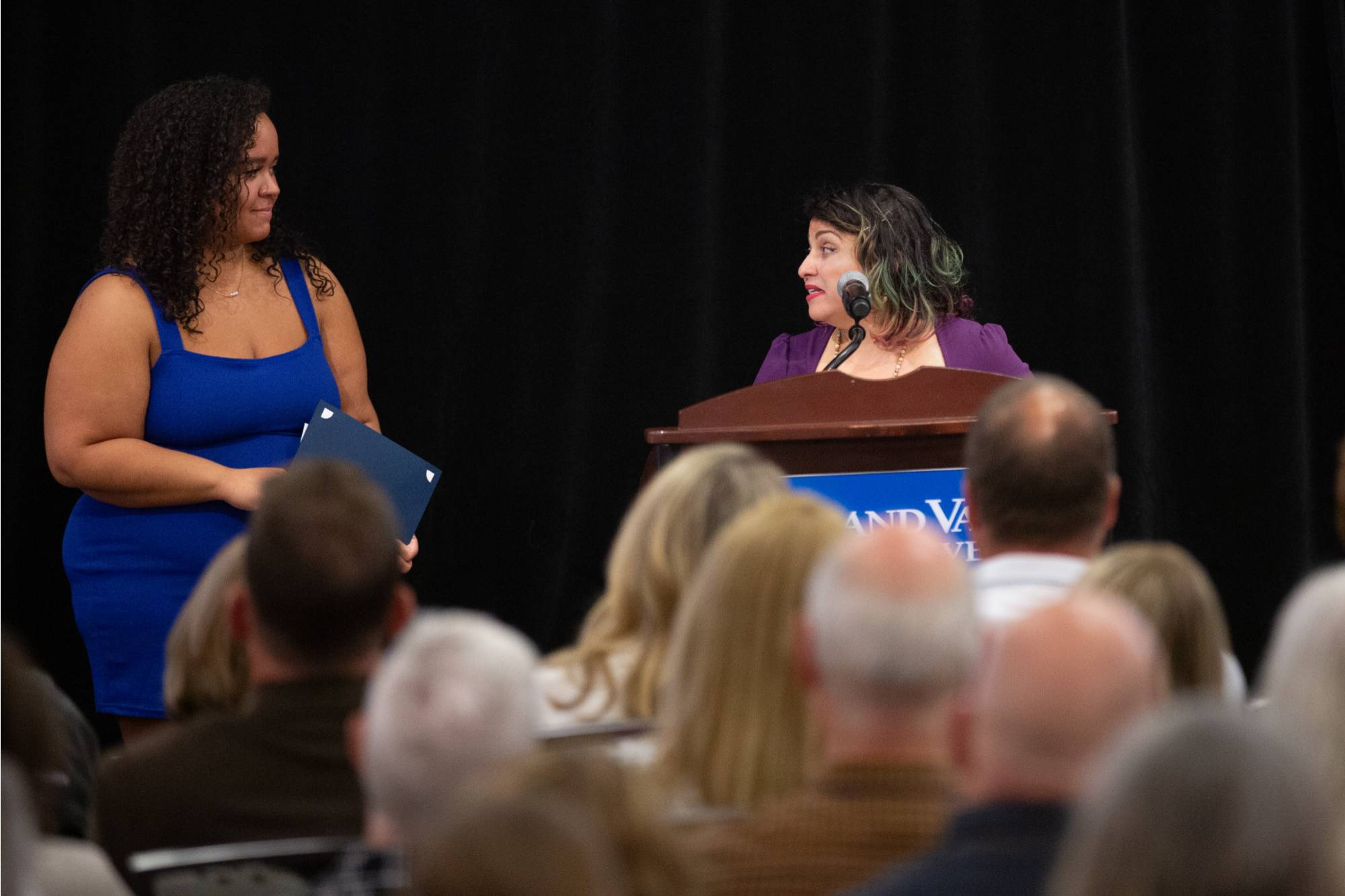 Professor Melba Velez Ortiz congratulates a student and speaks to the crowd.